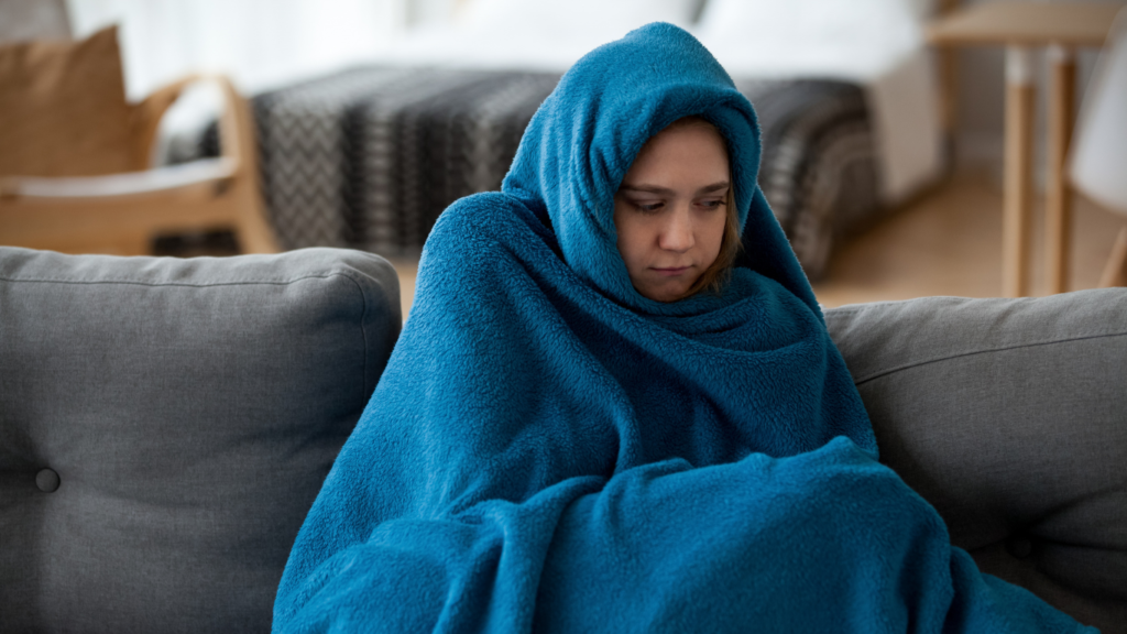 Girl covered in a blanket cold at home