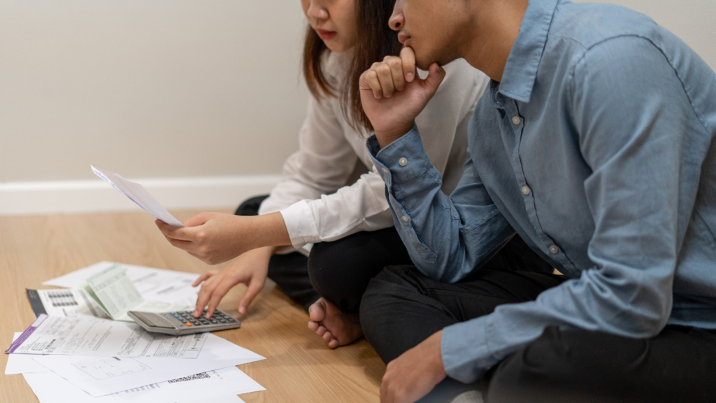 Couple sitting on the floor with papers calculating their expenses