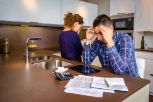 Man and woman in the kitchen, looking stressed over finances