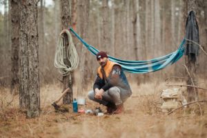 Man in wilderness setting up camp with emergency tools